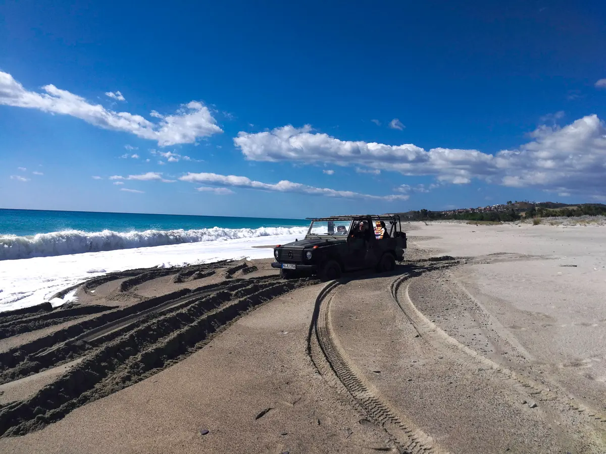 Geländewagen am Strand von Santa Caterina dello Ionio mit Wellen und blauem Himmel in Kalabrien